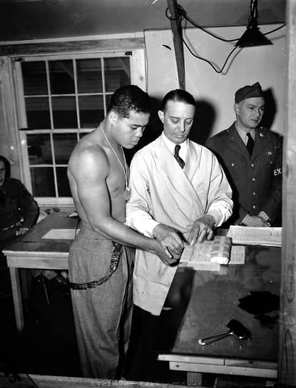 Американский боксер Джо Луис (слева) сдает отпечатки пальцев перед призывом в армию США, 1942 год
