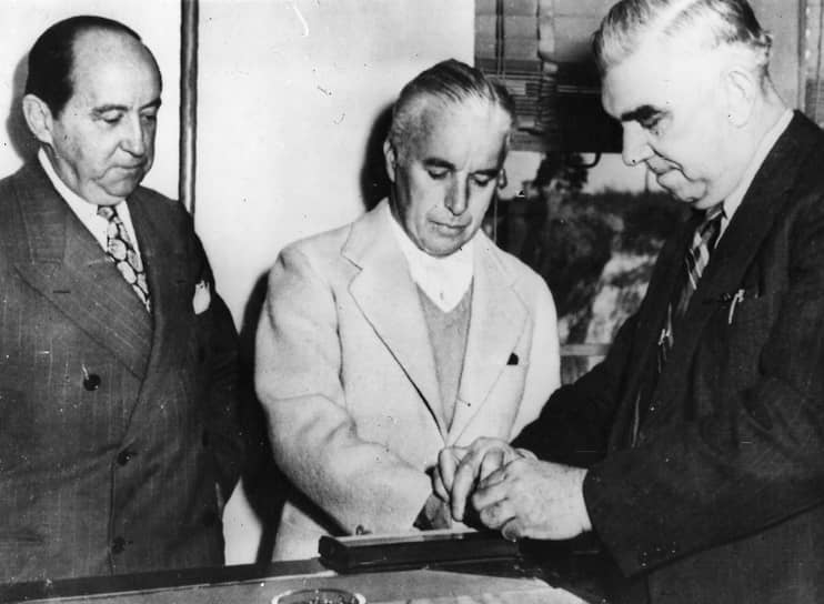Британский киноактер и режиссер Чарли Чаплин (в центре) проходит процедуру дактилоскопии перед визитом в США, 1944 год
