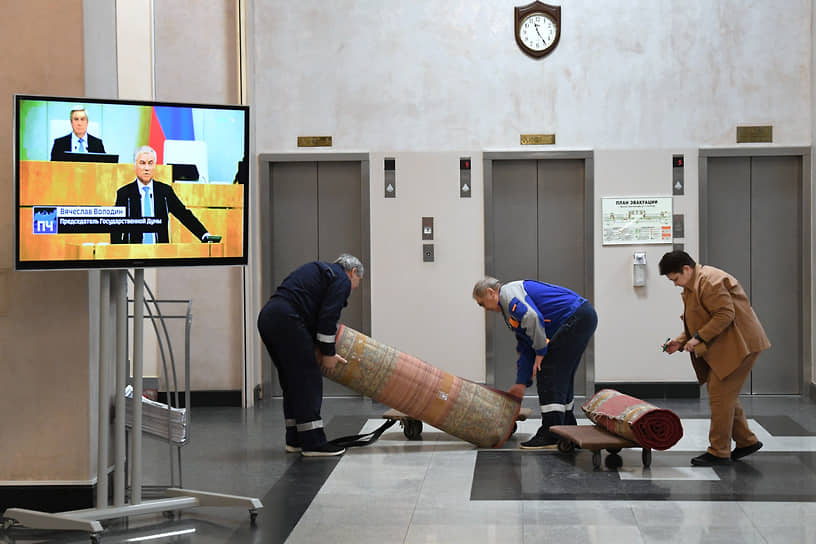 Сотрудники сервисной службы собирают ковры в холле здания Госдумы