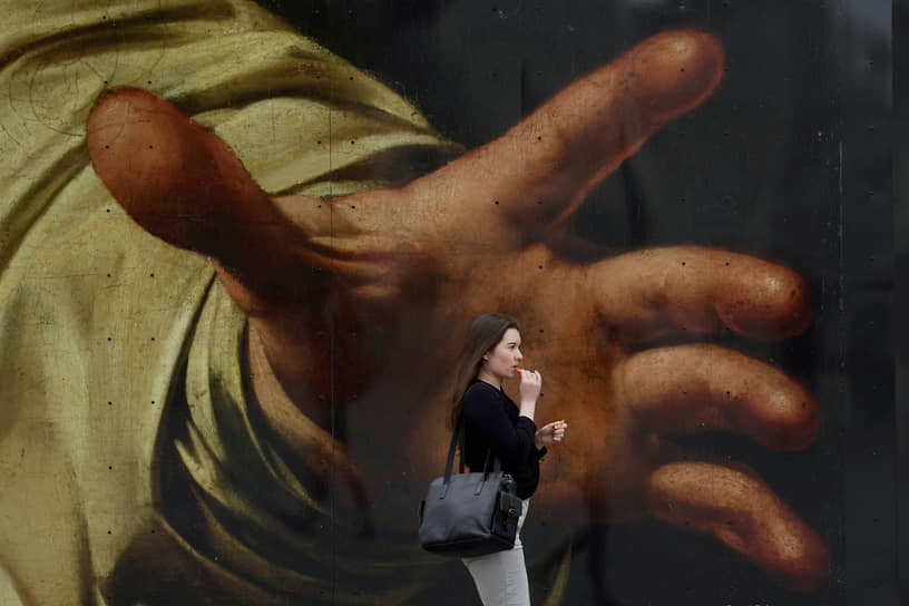 Лондон, Великобритания. Местная жительница проходит мимо плаката с картиной Караваджо «Ужин в Эммаусе» возле Национальной галереи 