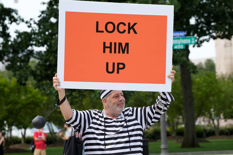 Участник акции держит плакат «Заприте его» перед зданием Федерального суда в Вашингтоне в день заседания по делу Дональда Трампа