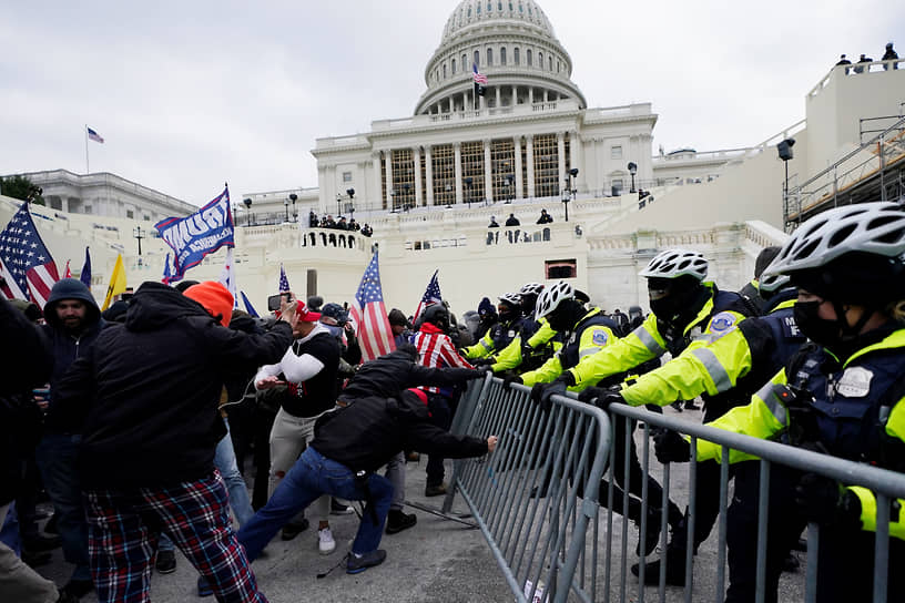 Сторонники президента Дональда Трампа пытаются прорваться через полицейский барьер у Капитолия в Вашингтоне в январе 2021 года