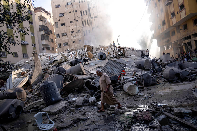 Палестинцы осматривают обломки здания после израильского авиаудара в секторе Газа