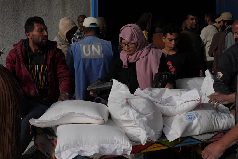 Палестинцы забирают пшеницу из распределительного центра ООН в лагере беженцев Бурейдж в секторе Газа