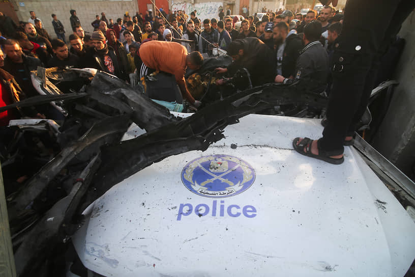 Палестинцы около поврежденной полицейской машины движения «Хамас» в Рафахе