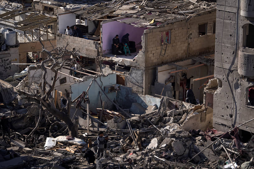 Палестинцы смотрят на разрушения после израильского удара по Рафаху