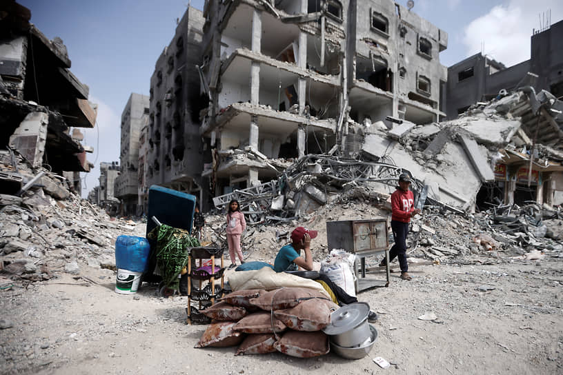 Палестинцы со своими вещами возле поврежденных домов в Хан-Юнисе в секторе Газа