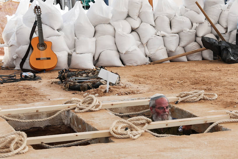 Мужчина копает могилу для убитой боевиками «Хамаса» семьи в Ган-Явне (Израиль)