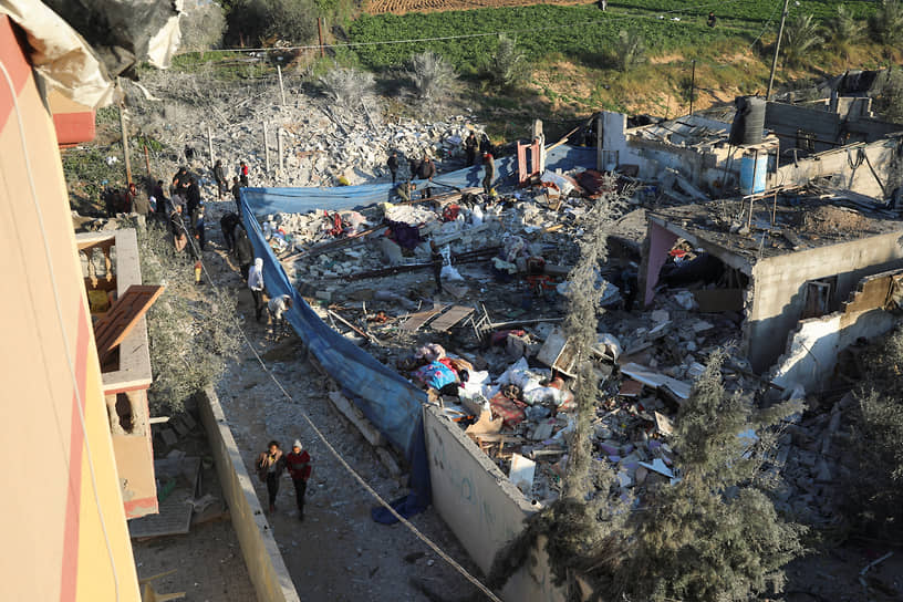 Палестинцы осматривают место ракетного удара по дому в Рафахе