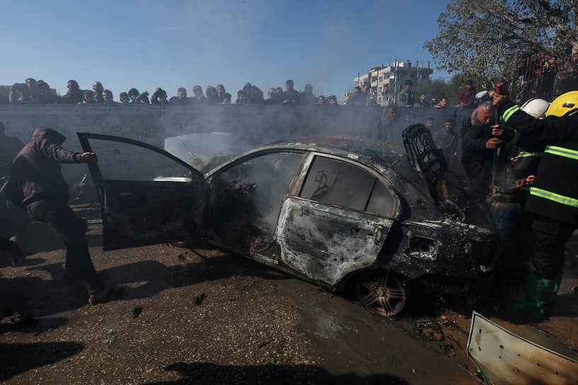 Палестинцы осматривают сгоревший автомобиль в Рафахе (сектор Газа)