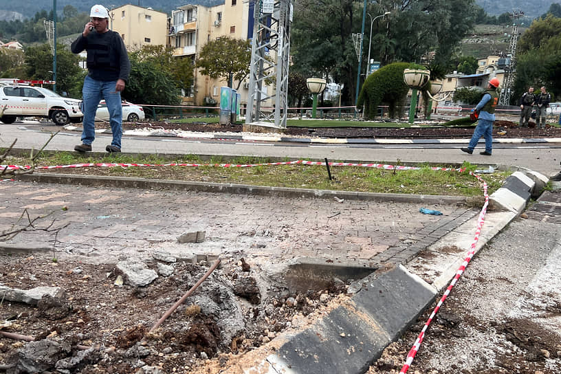 Рабочие на месте падения ракеты в Кирьят-Шмоне в Израиле