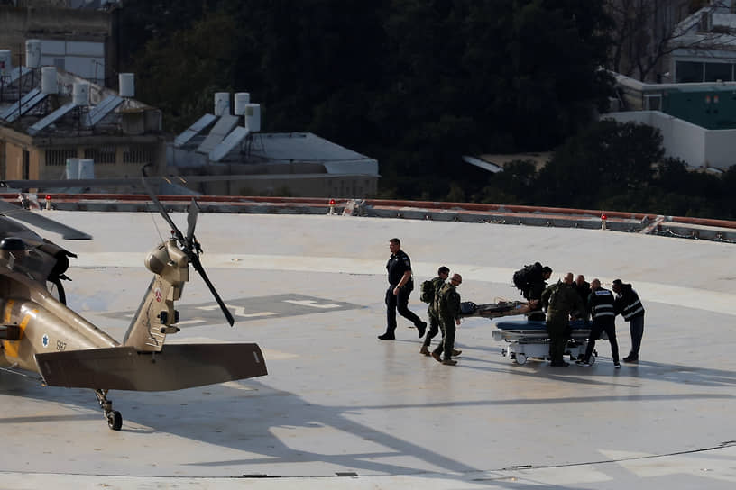 Пациента на носилках выносят из израильского военного вертолета на вертолетной площадке больницы в Тель-Авиве