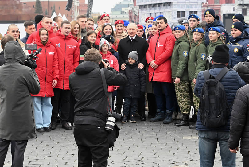 Президент России Владимир Путин (в центре) фотографируется с волонтерами, участниками поисковых движений и детьми погибших героев специальной военной операции 