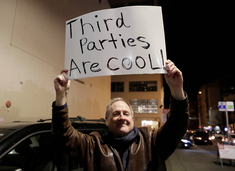 Сторонник Либертарианской партии Джефф Джаред держит плакат с призывом поддержать «третьи» партии