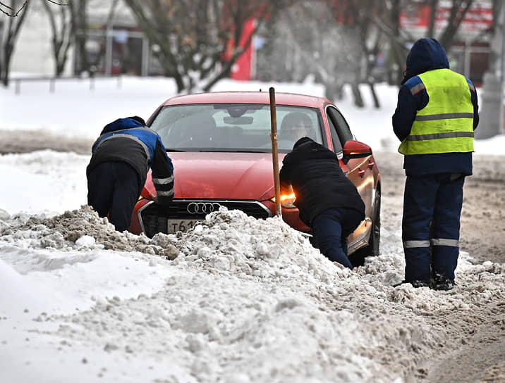 Сотрудники коммунальных служб города помогают вытолкнуть автомобиль из сугроба