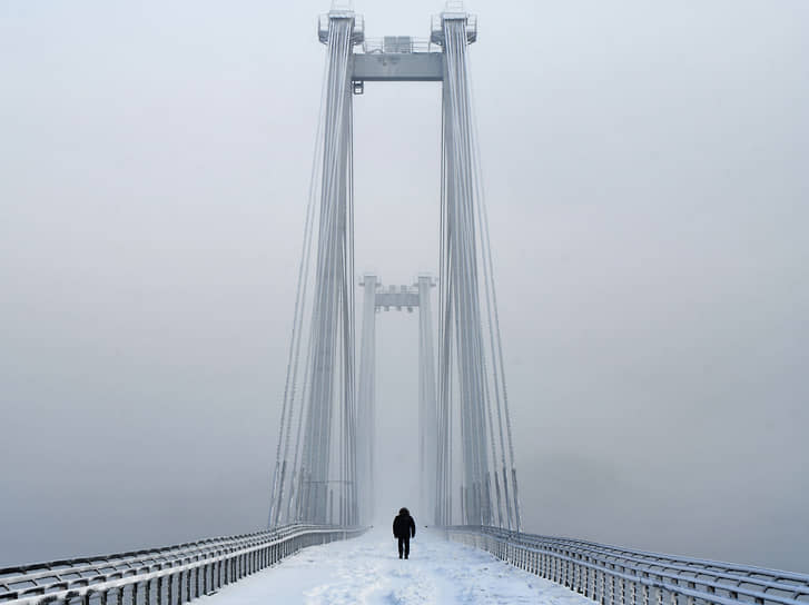 Красноярск. Пешеход идет по Виноградовскому мосту во время метели