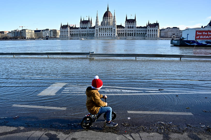 Будапешт, Венгрия. Мальчик едет на велосипеде по затопленной набережной