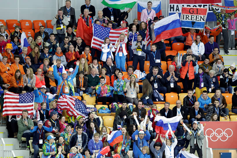 Болельщики размахивают национальными флагами, наблюдая за женским забегом на 3000 м в конькобежном центре «Адлер-Арена»