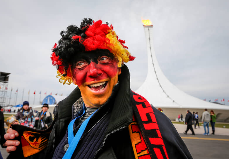 Гость из Германии улыбается на фоне олимпийского огня 