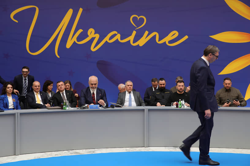 Президент Украины Владимир Зеленский (второй справа за столом) на Балканском саммите по Украине смотрит на проходящего мимо президента Сербии Александра Вучича
