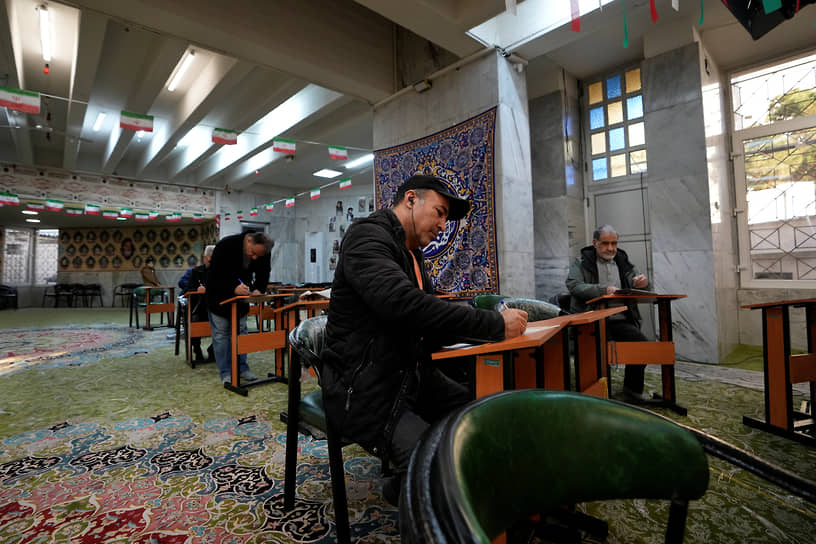 Избиратели заполняют бюллетени на избирательном участке в Тегеране
