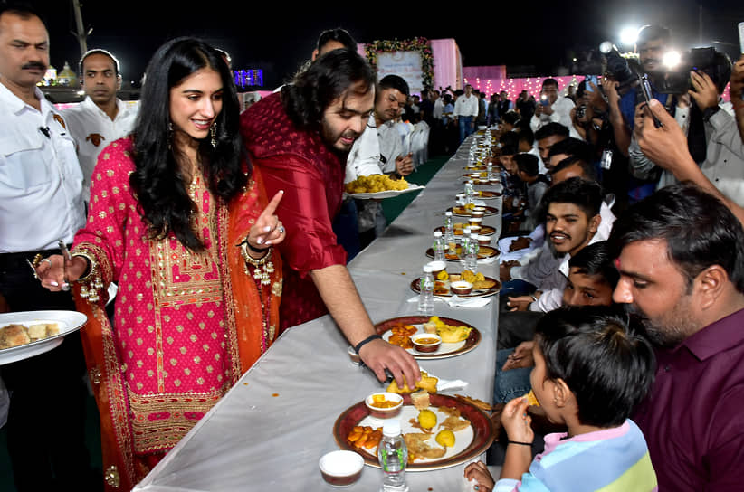 Будущие супруги (на фото оба в красном) организовали ужин для более чем 50 тыс. жителей поселка Джамнагар, рядом с которым находится семейное предприятие Амбани — главный нефтеперерабатывающий завод Reliance 