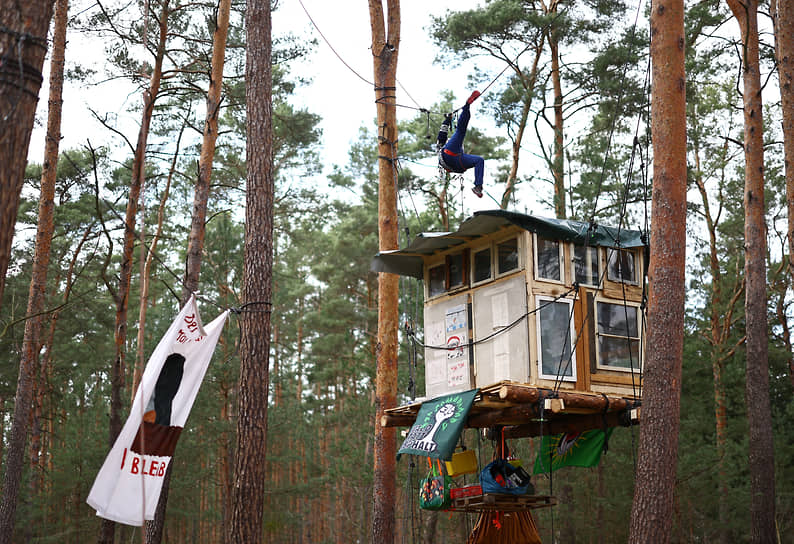 Грюнхайде, Германия. Экоактивист поднимается над домом на дереве, установленным в лесу в знак протеста против расширения завода Tesla Gigafactory