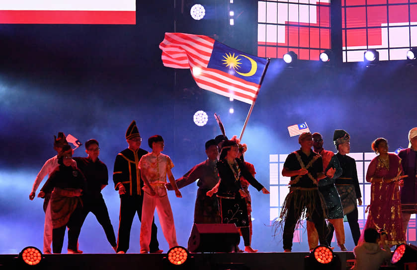 Во второй части церемонии артисты исполняли песни на разных языках мира — испанском, китайском, арабском, хинди и т.д.
&lt;br>На фото: участники фестиваля с флагом Малайзии 