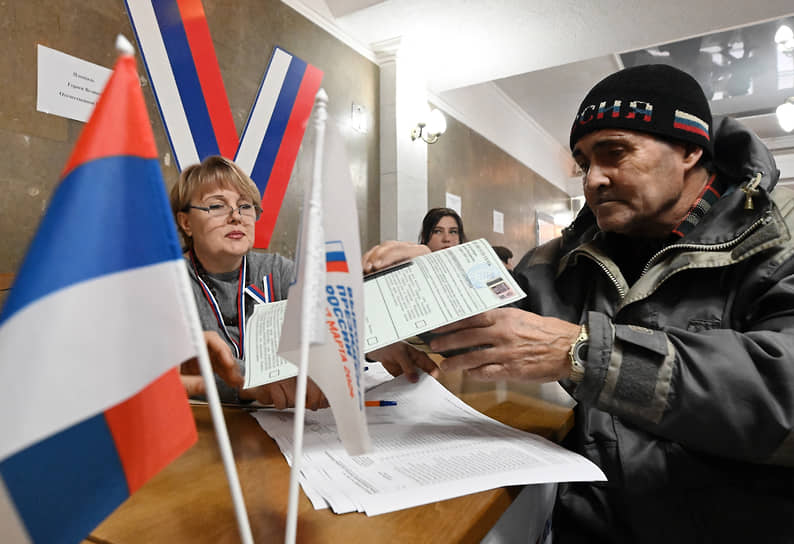 Луганск. Мужчина получает бюллетень для голосования 