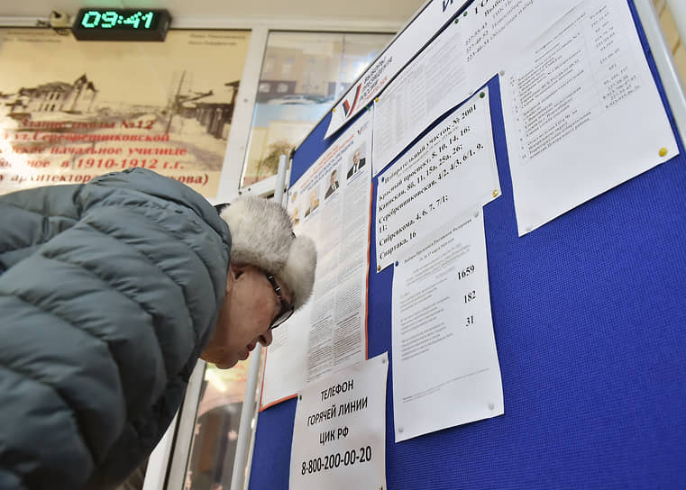 Новосибирск. Мужчина изучает информационный стенд на избирательном участке