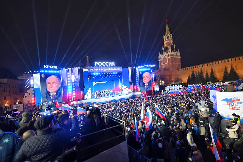 Участники митинга-концерта слушают речь президента России Владимира Путина (на экране) 