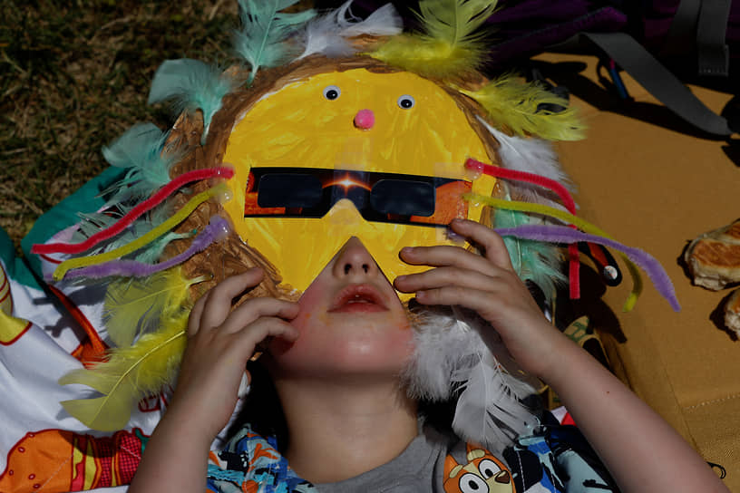 Девочка готовится наблюдать солнечное затмение в Блю-Маунд (США)