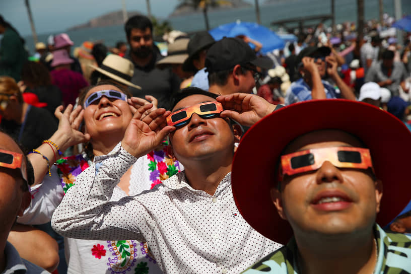Люди в защитных очках наблюдают затмение в Масатлане (Мексика)