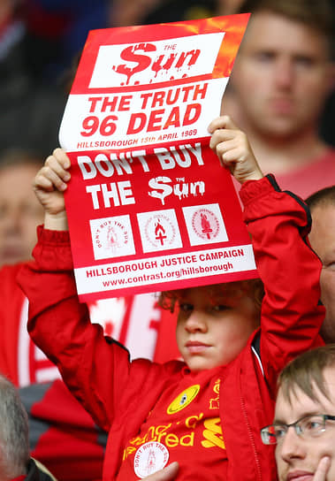 Юный болельщик держит плакат с призывом не покупать газету The Sun
