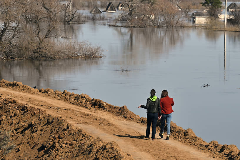 Местные жительницы идут по защитной насыпи вдоль реки Ишим