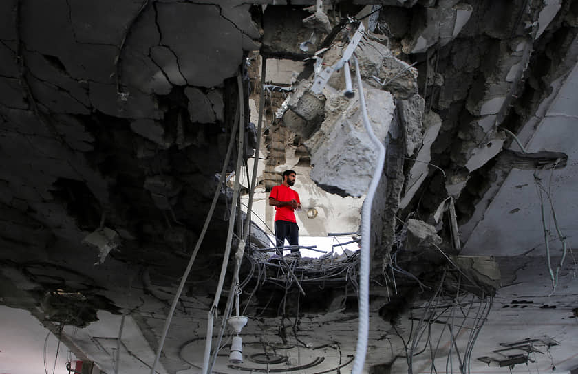 Человек стоит в руинах здания, разрушенного в результате израильского обстрела