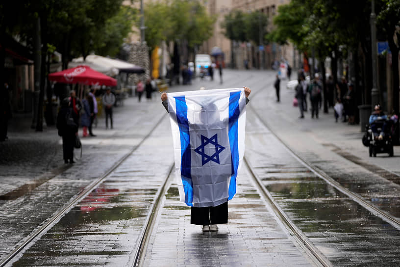 Иерусалим. Женщина держит флаг Израиля, пока звучит двухминутная сирена в память о жертвах Холокоста 