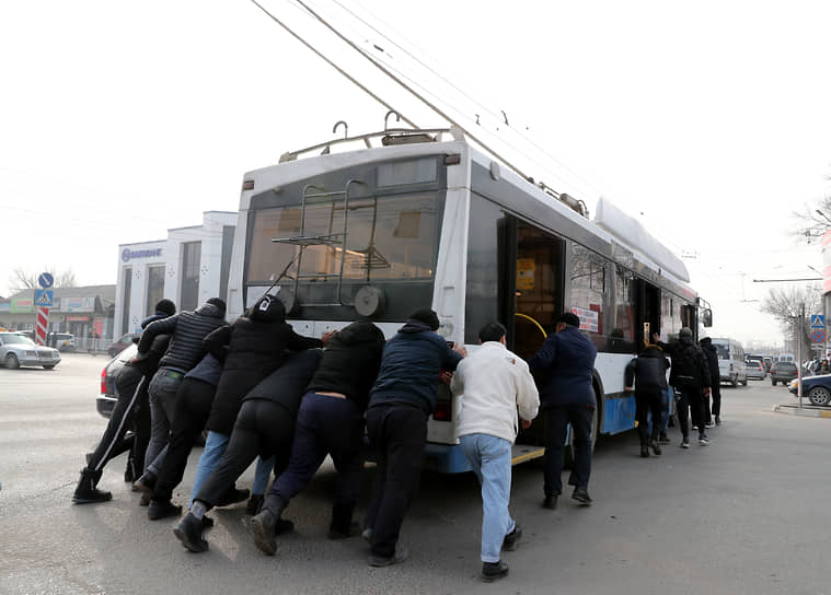 Люди толкают троллейбус, который не может ехать из-за блэкаута