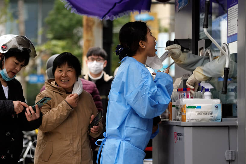 Женщина сдает тест на коронавирус в Шанхае