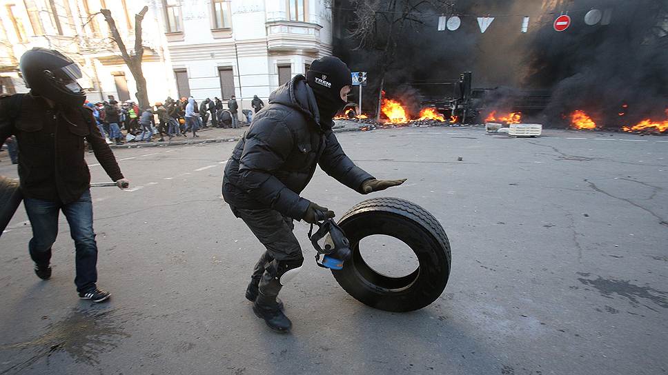 Во время противостояния на улице Институтской. Активисты Майдана катят покрышку к баррикаде, чтобы сжечь. 
