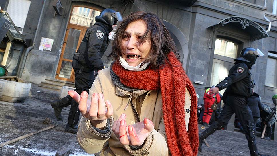 Сотрудники милиции проходят мимо плачущей женщины после разгона на улице Институтской.
