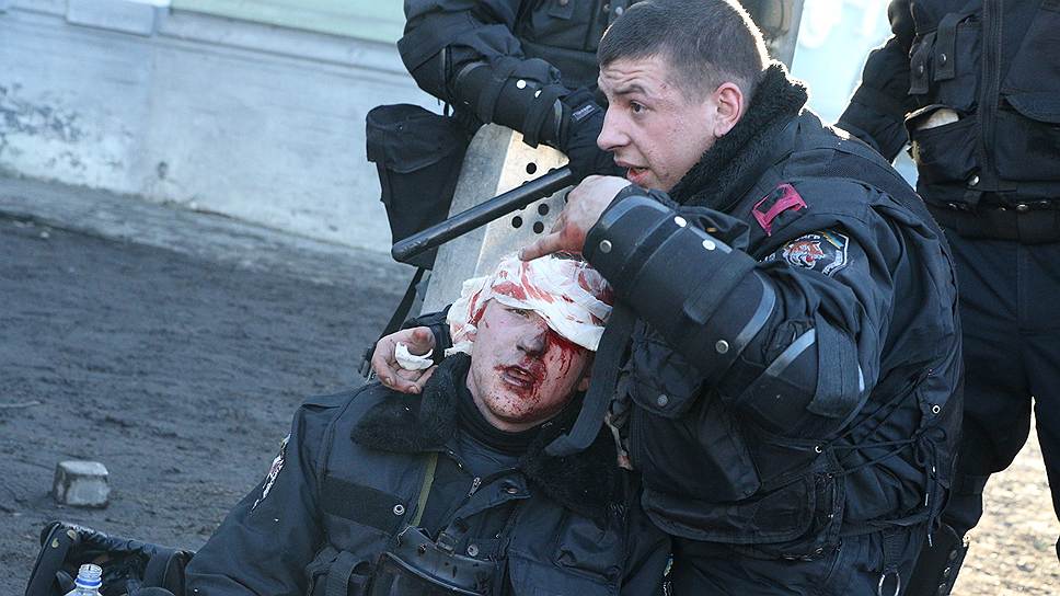 Милиционер оказывает помощь коллеге после разгона на улице Институтской.
