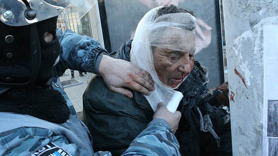 Сотрудник спецподразделения милиции &quot;Беркут&quot; оказывает помощь пострадавшему после разгона на улице Институтской.
