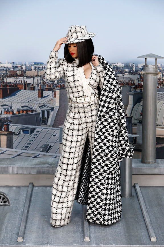Тепленький total look Chanel выбрала Карди Би, прибывшая на показ бренда в Париже. Твидовый комбинезон она дополнила шляпкой и пальто с принтом «гусиная лапка». 