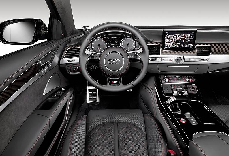 Внутри S8 Plus напоминает A8 в наиболее роскошном исполнении. Отличительные особенности: вместо ценных пород дерева — карбон и искусно обработанный алюминий, черная матовая кожа с красной прострочкой, черная алькантара на дверных панелях, потолке и задней полке
