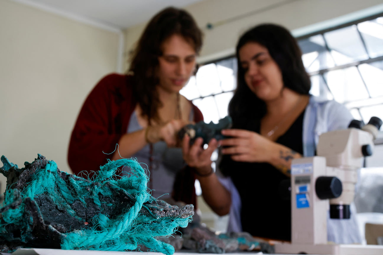 Исследователь Фернанда Авелар Сантос (на фото — справа) держит «пластиковые камни», найденные на острове Триндади в штате Эспириту-Санту. Бразилия, 7 марта 2023 года