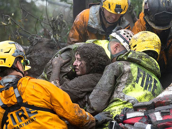 Монтесито, Калифорния. Спасатели помогают местной жительнице покинуть разрушенный дом. Оползни беспрепятственно сошли с холмов Южной Калифорнии, так как растительность, которая могла помешать этому, была сожжена лесными пожарами в прошлом месяце