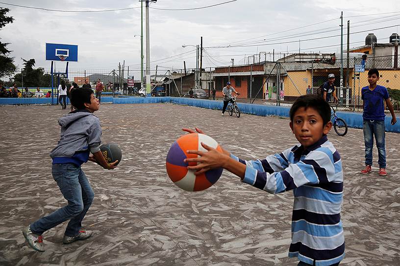 Дети играют на баскетбольной площадке, покрытой вулканическим пеплом, в столице Гватемалы 
