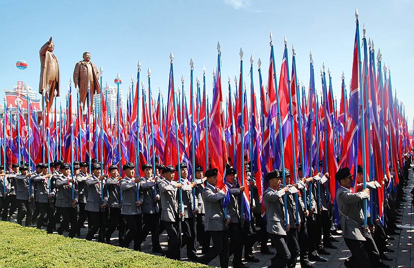 Участники парада несут национальные флаги Корейской народно-демократической республики