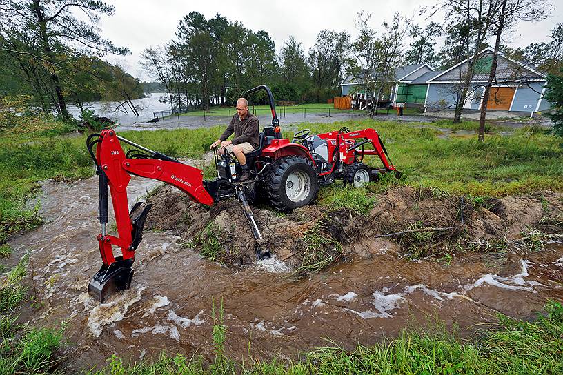 Житель Северной Каролины копает траншею, чтобы отвести воду от своего дома